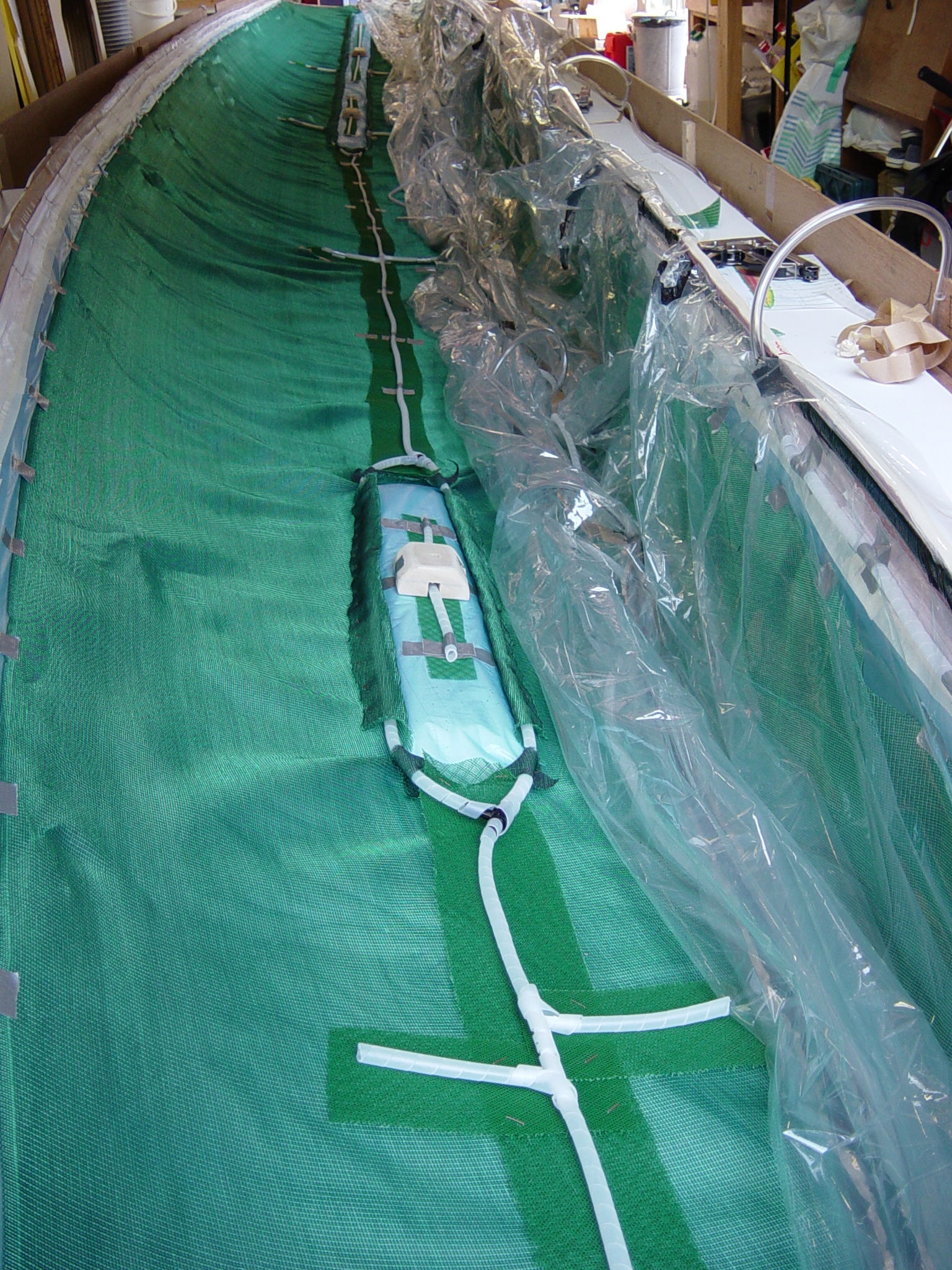 Resin infusion setup for the second hull half with vacuum bag, distribution media, and controlled resin flow.