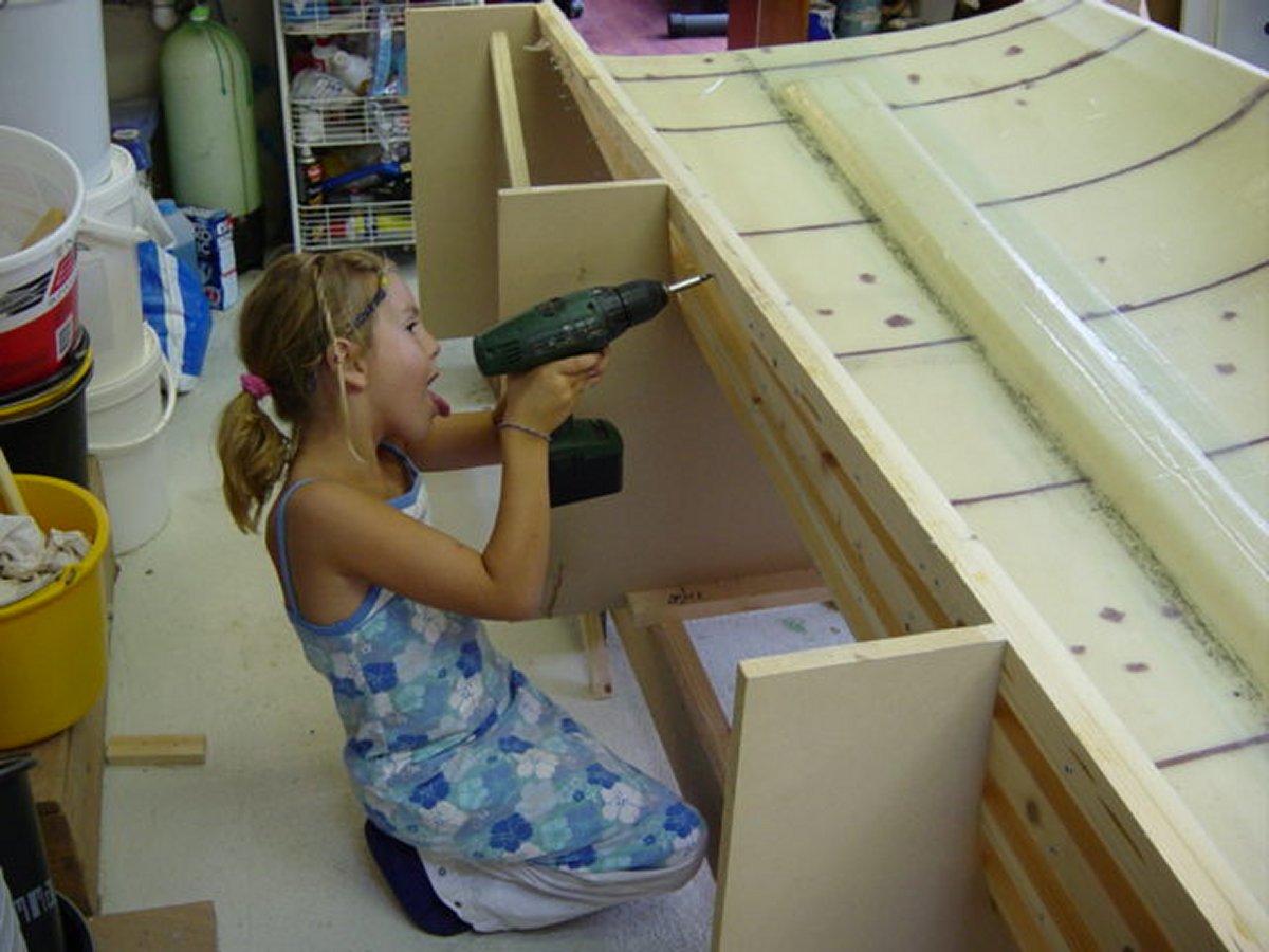 Planking the second hull half: mirrored frame setup, removable battens, and foam strips shaped around the raised-deck overhang.